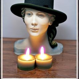 Sculpted candles with a Fedora Hat design beside a computer
